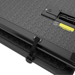 A 04-15 Nissan Titan fibreglass quad-fold tonneau cover showing the safety buckle and strap locking system on a pickup truck bed cover.